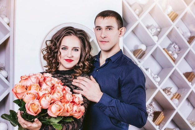 Man gives a woman a bouquet of flowers in the interior of the house