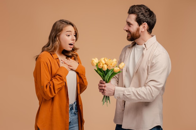 Man giving bouquet of beautiful tulips flowers for young surprised woman Couple dating love