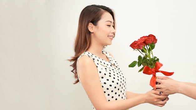 白い背景で隔離の驚いた女性に赤いバラの束を与える男