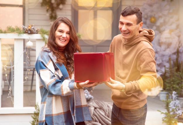 Photo man giving a christmas present to his girlfriend they holding red box with valentines gift