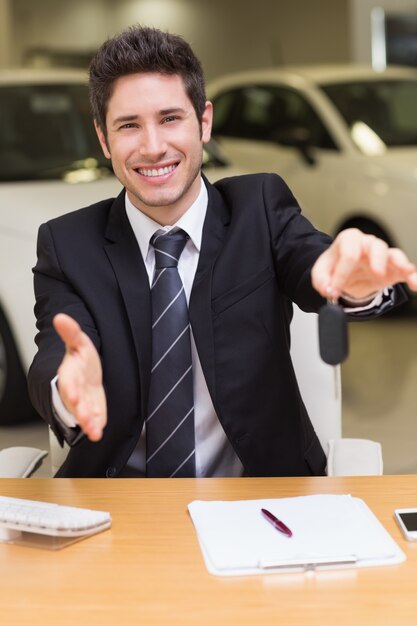 Man giving a customer keys while reaching for handshake