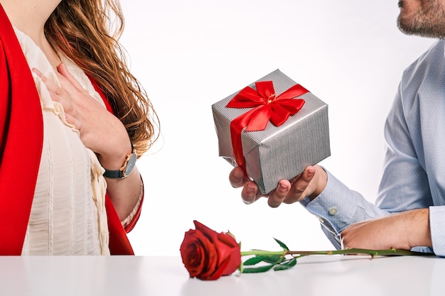 彼のパートナーに贈り物と赤いバラを与える男。バレンタインデーと恋にカップルの概念。