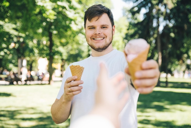 Man giving ice cream in hot sunny day in city park first person point of view reach out hand