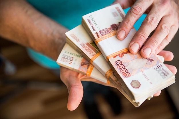 Man giving money Russian Ruble banknotes over his desk in a dark office bribery and corruption conceptrussian rubles banknotes Financial themestack of banknotes in a man's hand