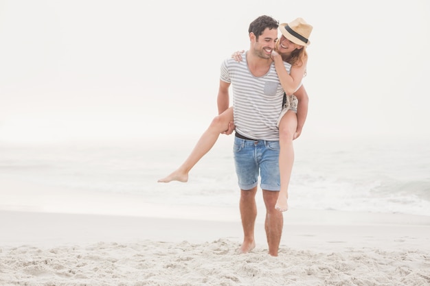 Man giving a piggy back to woman on the beach