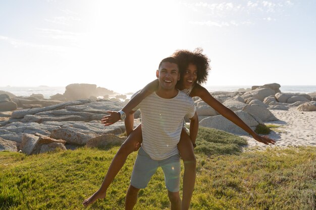 Man giving piggyback ride to woman at beach