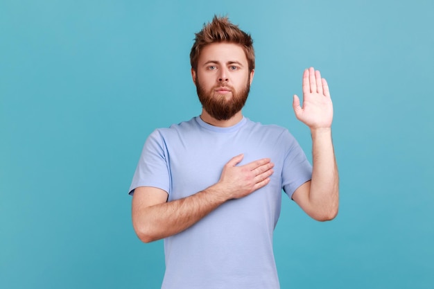 Foto uomo che dà promessa con la mano sul cuore giurando fedeltà dando voto con faccia seria responsabile