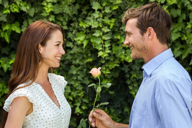 Man giving rose to woman at front yard