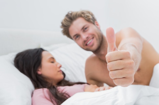 Man giving thumb up next to his sleeping wife