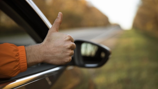 Человек, поднимающий большой палец из своей машины во время поездки высококачественной красивой фотоконцепции