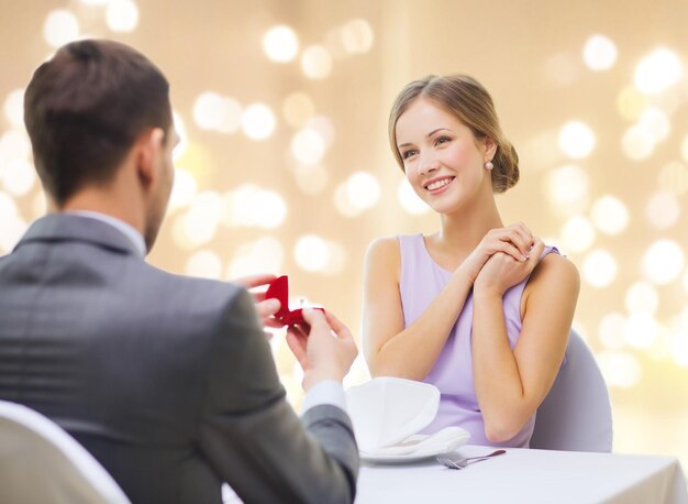 man giving woman engagement ring at restaurant