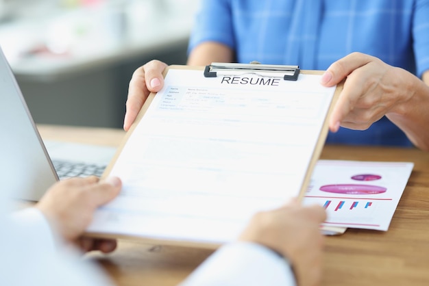 Man giving woman resume for employment in office closeup unemployment concept