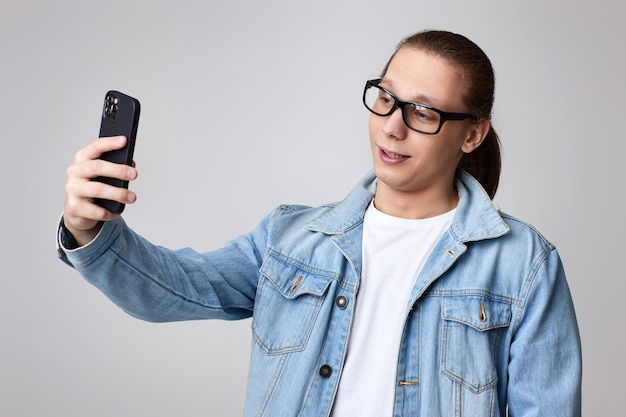 Man in glasses and jeans jacket making selfie