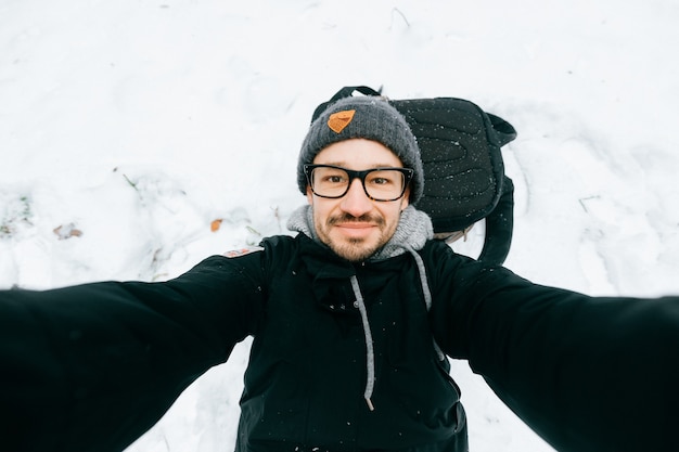 雪の中で自分撮りをしている眼鏡の男