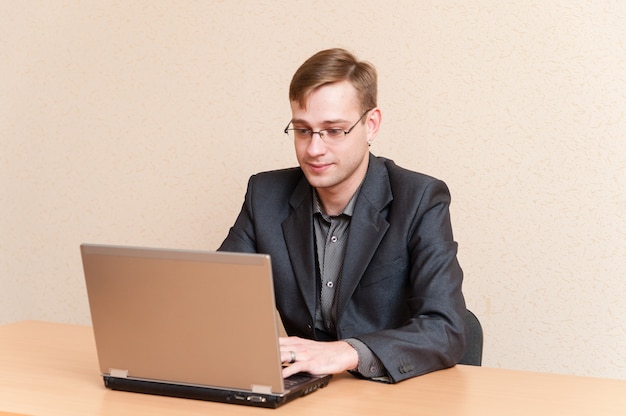 Man in glasses works for laptop