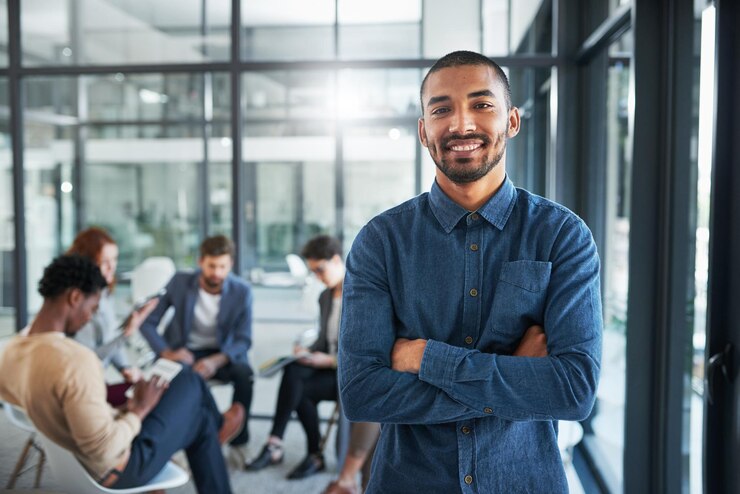 Foto man glimlachend en enthousiast op kantoor portret voor nieuwe kansen stage of werk persoon gelukkig en collega's die zich op de achtergrond ontmoeten voor samenwerking teamwerk en partnerschap op de werkplek