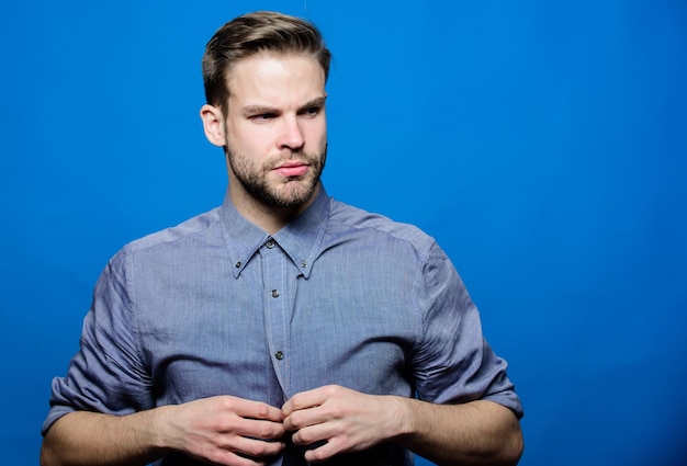 Man goed verzorgde baard Goed verzorgde macho Kapper en baardverzorging Baardverzorgingssalon Kapperssalon Baardverzorging Maak u klaar voor een date Hipster denim overhemd ziet er aantrekkelijk uit blauwe achtergrond