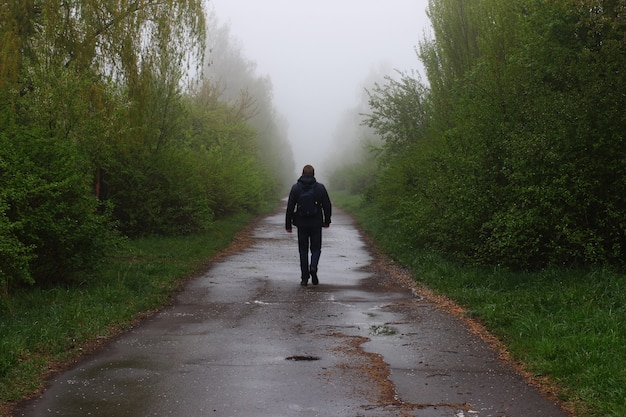 Мужчина идет по дороге в тумане