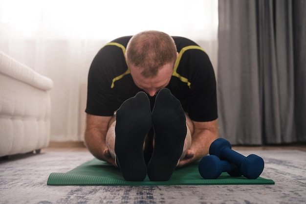 A man goes in for sports on a gym mat while bending forward