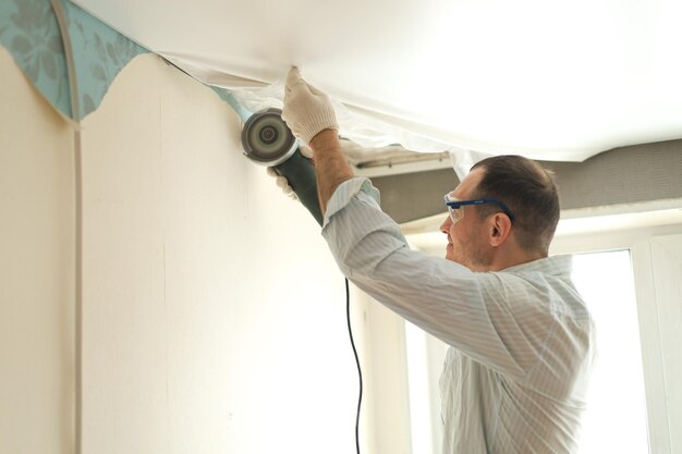 A man in goggles and gloves makes repairs while standing with a\
construction tool in his hands