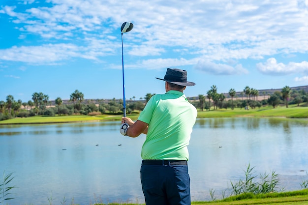 Man golfen bij een meer kijken naar de lancering van de bal