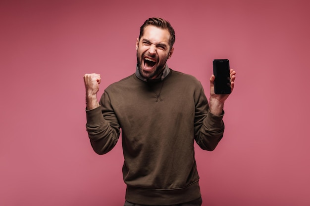 Man in good humor holding black smartphone on isolated background