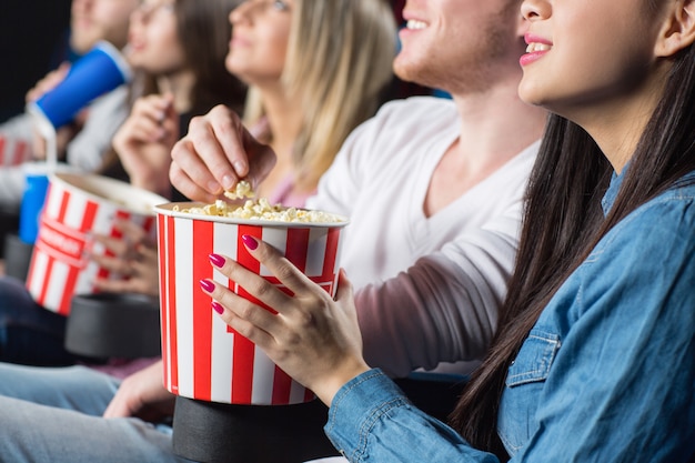 man grabbing popcorn from his female friend at the movie theatre