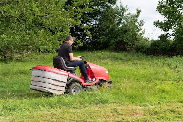 Man grasmaaier rijdt door grote groene weidetuin