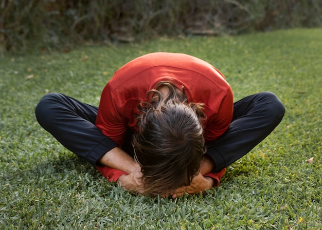 Foto uomo sull'erba all'aperto che fa yoga