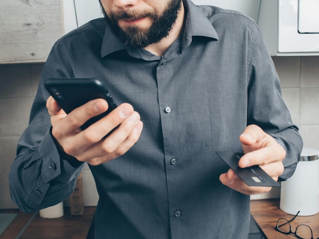 Photo man in gray button up long sleeve shirt holding black smartphone stock photo