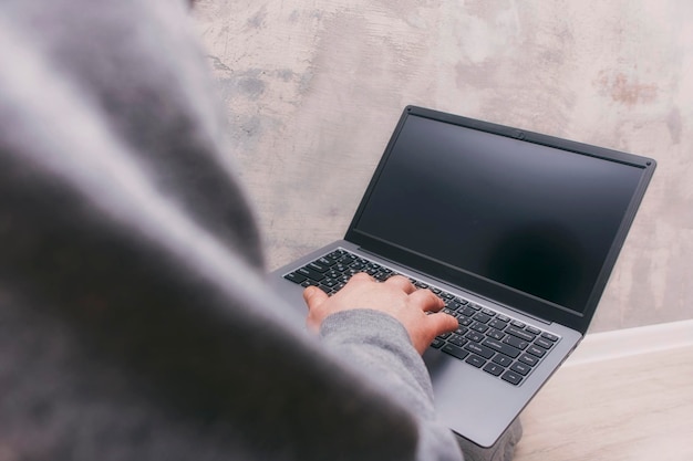 Man in gray clothes sits with a laptop against a concrete wall Freelancer's loft interior