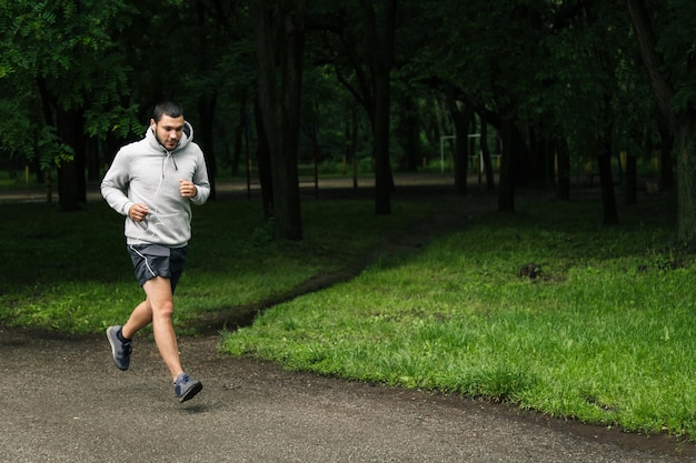 Man in the gray hoodie and headphones running in the park