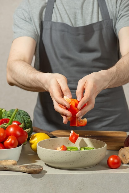 A man in a gray kitchen apron prepares a salad closeup