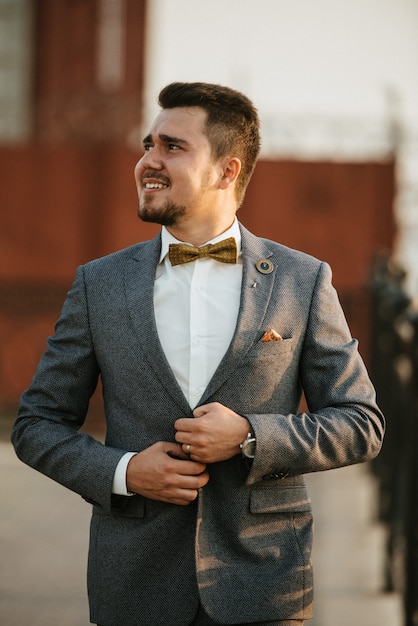 灰色のスーツを着た男性が路上でポーズをとり、紳士服を宣伝します。紳士服店の撮影
