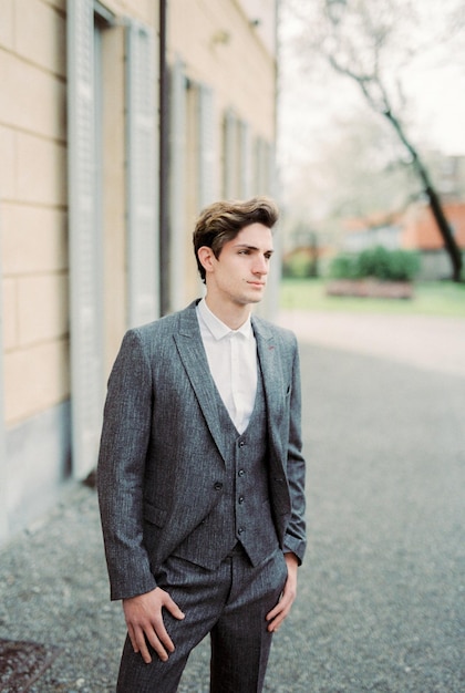 Man in a gray suit stands near an old villa Como Italy