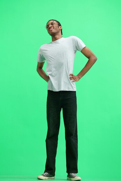 A man in a gray tshirt on a green background in full height warming up