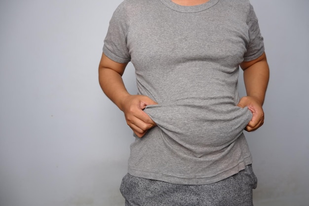 Man in gray tshirt holding and lifting his fat flabby belly