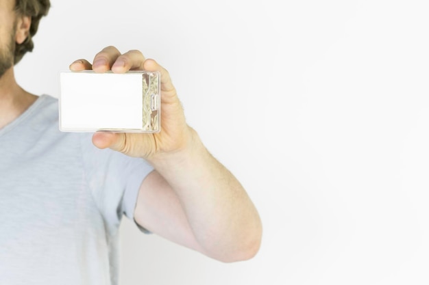 a man in a gray tshirt shows an empty badge in a plastic case