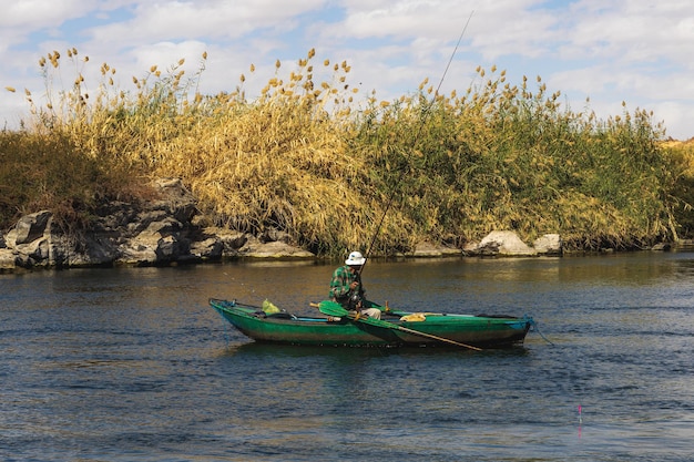 A man in a green kayak is sailing on the river.