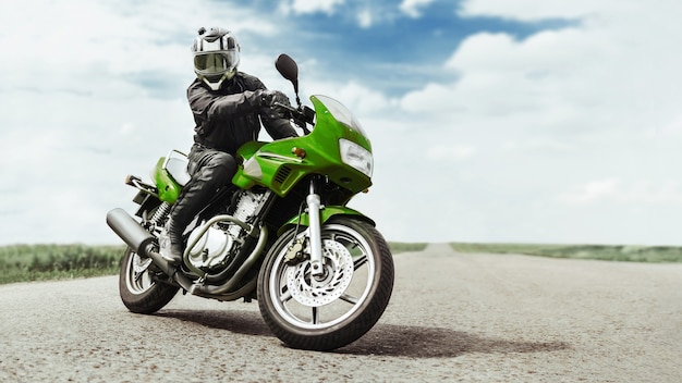 Foto un uomo su una moto verde si gira davanti alla telecamera