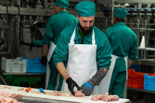 Мужчина в зеленом халате режет мясо на разделочной доске