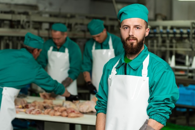 A man in a green uniform stands in front of a bunch of meat on a table.