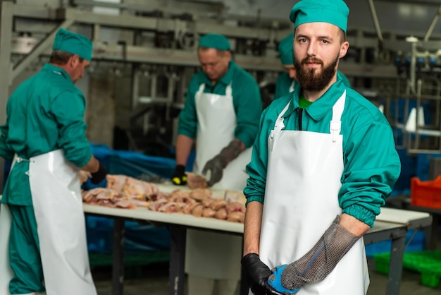 A man in a green and white uniform stands in front of a table of meat.