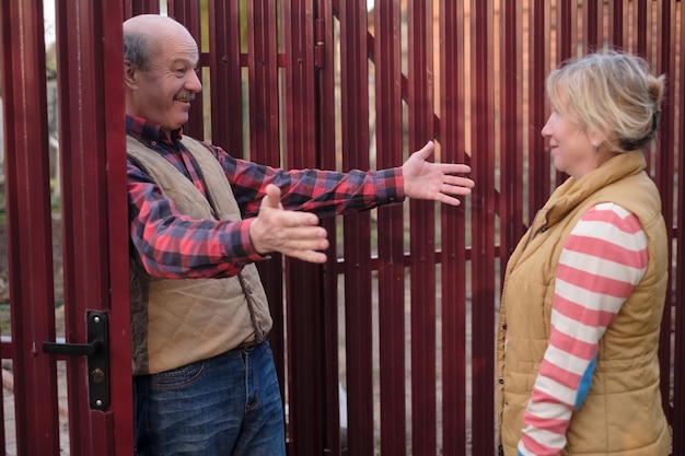 Man greeting his friend near red fence wanting to hug her