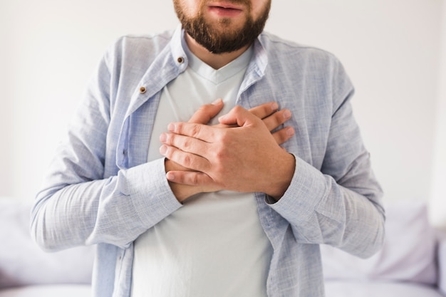 Uomo in camicia grigia che ha mal di cuore