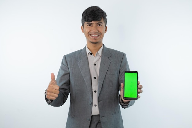 A man in a grey suit holds a green screen on white background