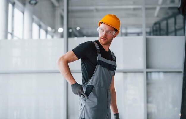 Man in grey uniform works indoors in modern big office at daytime