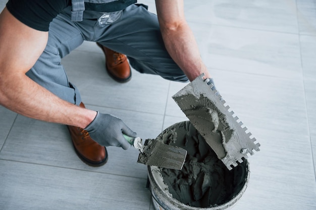 Man in grey uniform works with plate indoors in modern big office at daytime