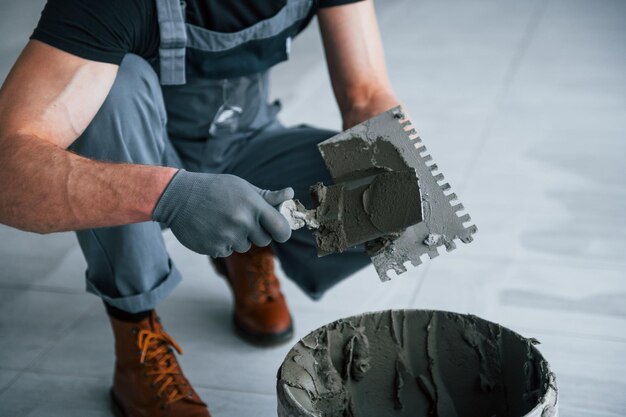 Man in grey uniform works with plate indoors in modern big office at daytime