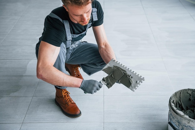 灰色の制服を着た男は、昼間は現代の大きなオフィスの屋内でプレートを操作します